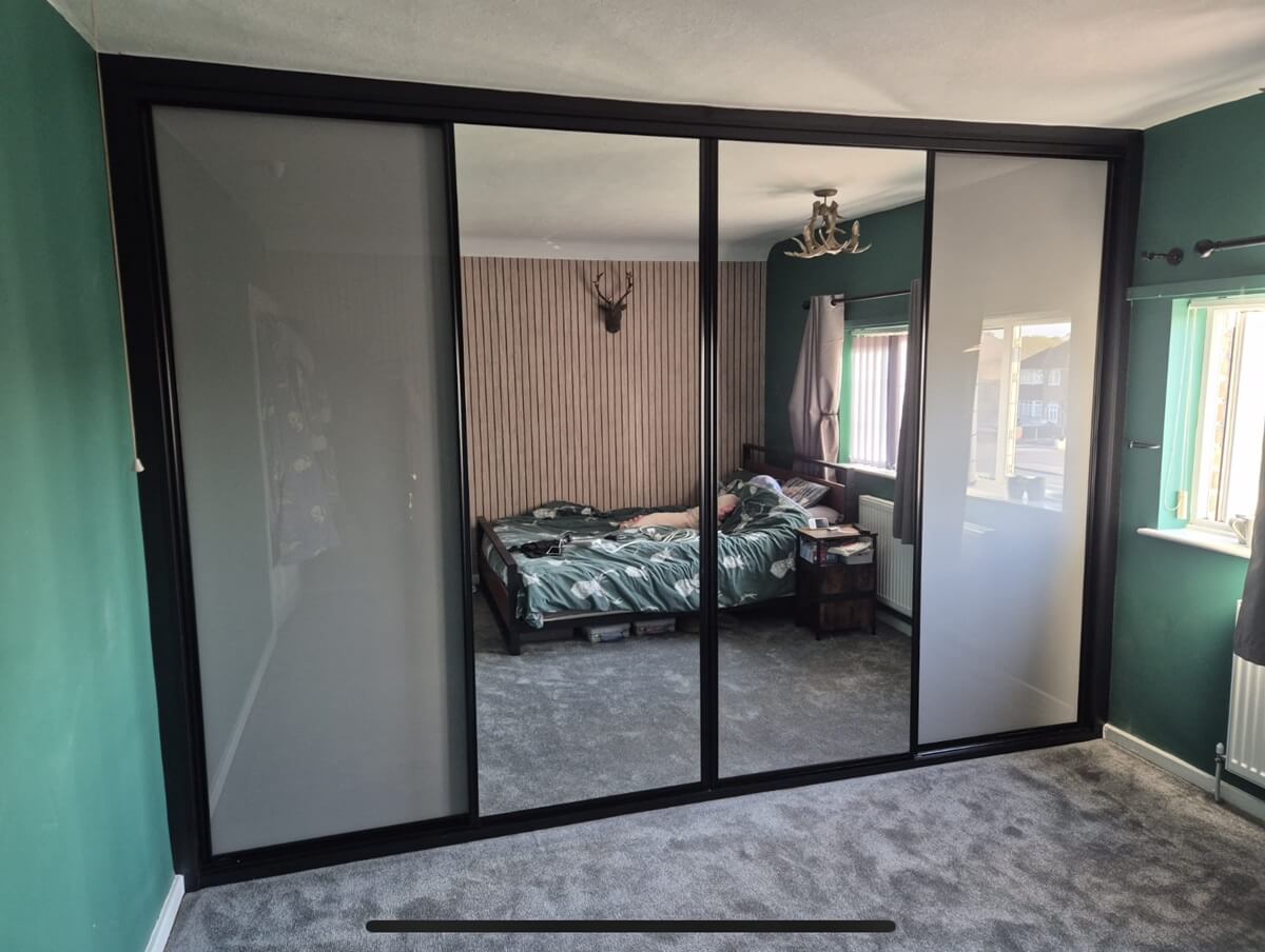 Black-framed ADAPT sliding wardrobe with chalk grey glass and silver mirror doors in a Walsall bedroom