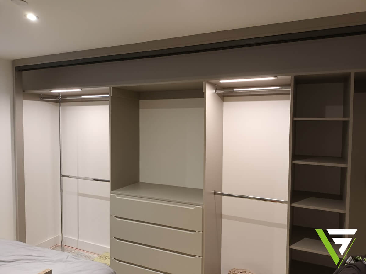Open fitted wardrobe interior in Aldridge showing chrome hanging rails, open shelving and a drawer stack with integrated LED lighting