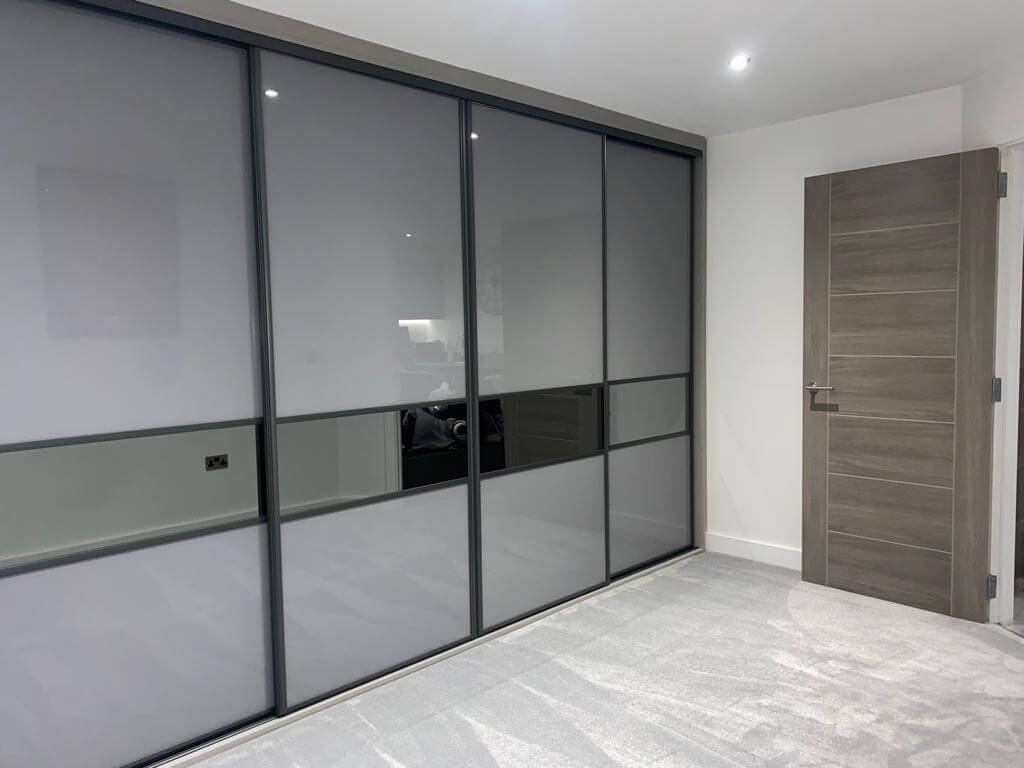 Open sliding wardrobe interior in Aldridge fitted with a central TV recess, drawers and hanging space either side