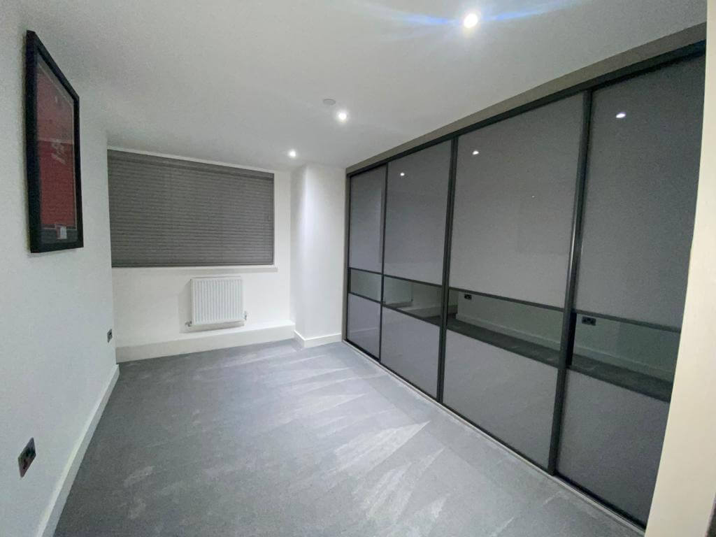 Fitted sliding wardrobe in Aldridge with a dark grey frame and smoked mirror-panel doors