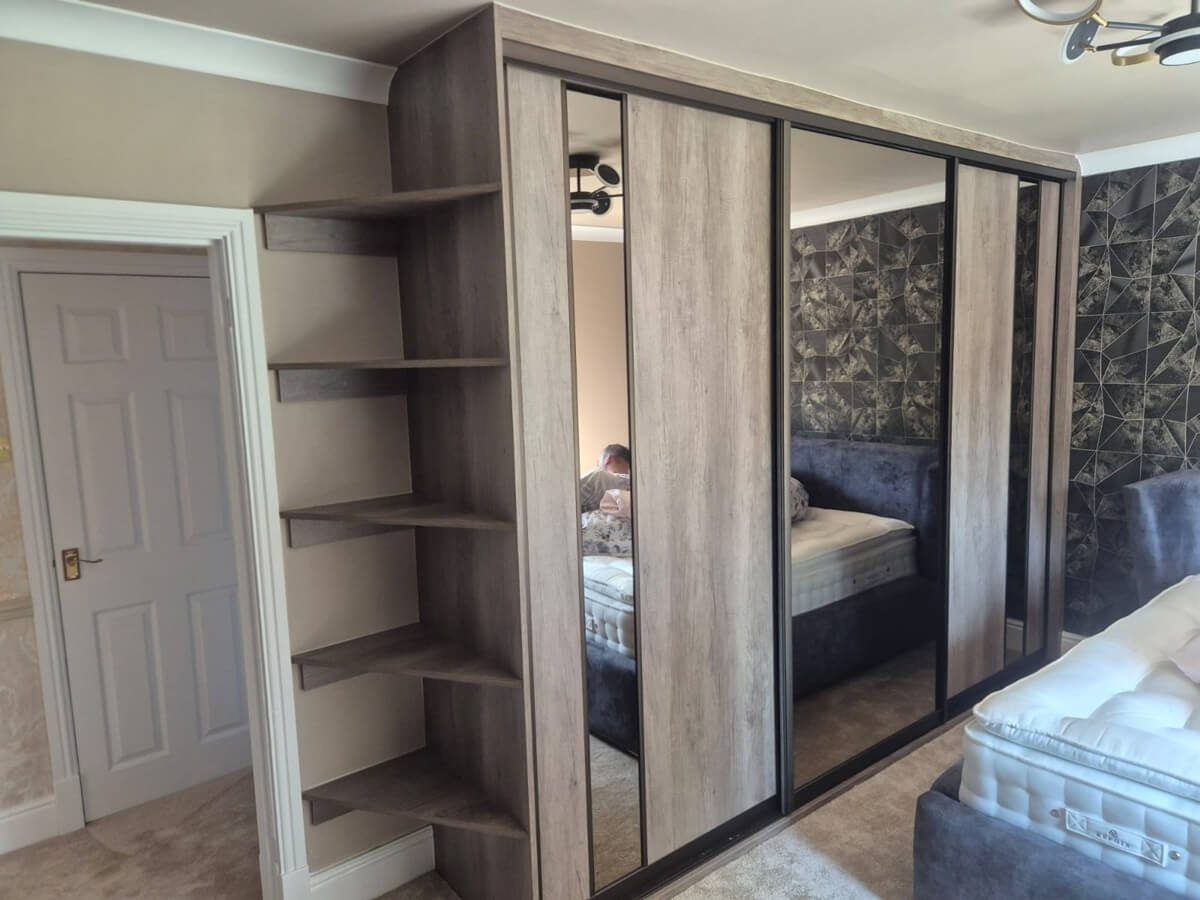 A Cannock bedroom in our FORM range - Cashmere frame, two full-panel silver mirror doors and two cashmere glass doors with a natural Bardolino oak split, finished with an open corner shelf tower.