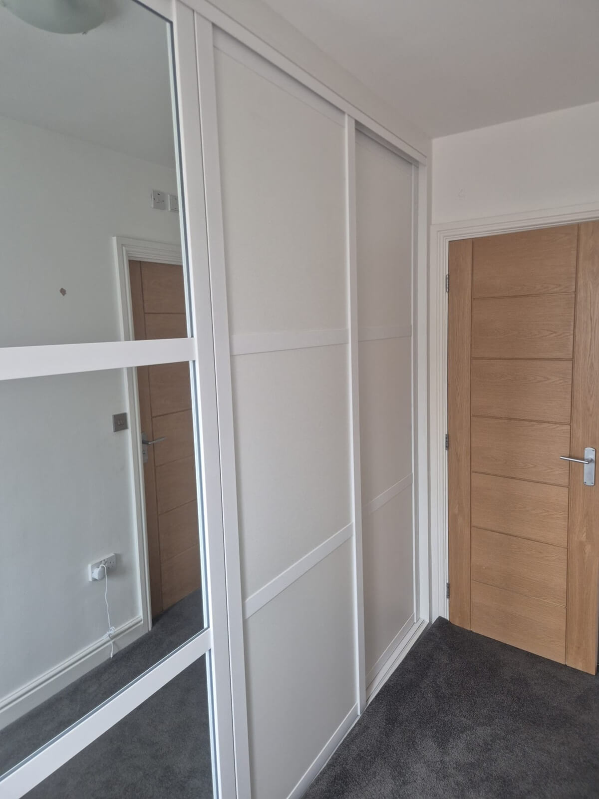 White sliding wardrobe with a full mirror door, fitted into a landing alcove