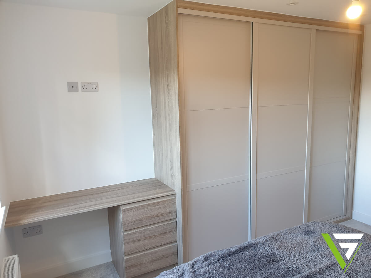Oak-effect desk with three drawers built in beside Cashmere SHAKER sliding wardrobe doors in a Stafford bedroom