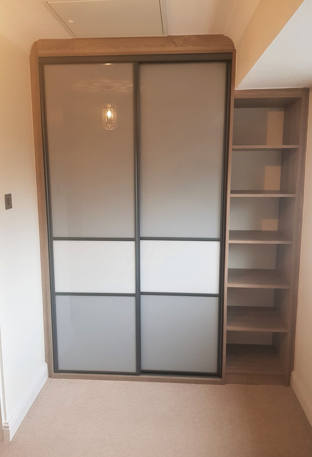 Two-door Storm Grey sliding wardrobe in white oak woodwork with an open shelf tower beside it, in Stafford