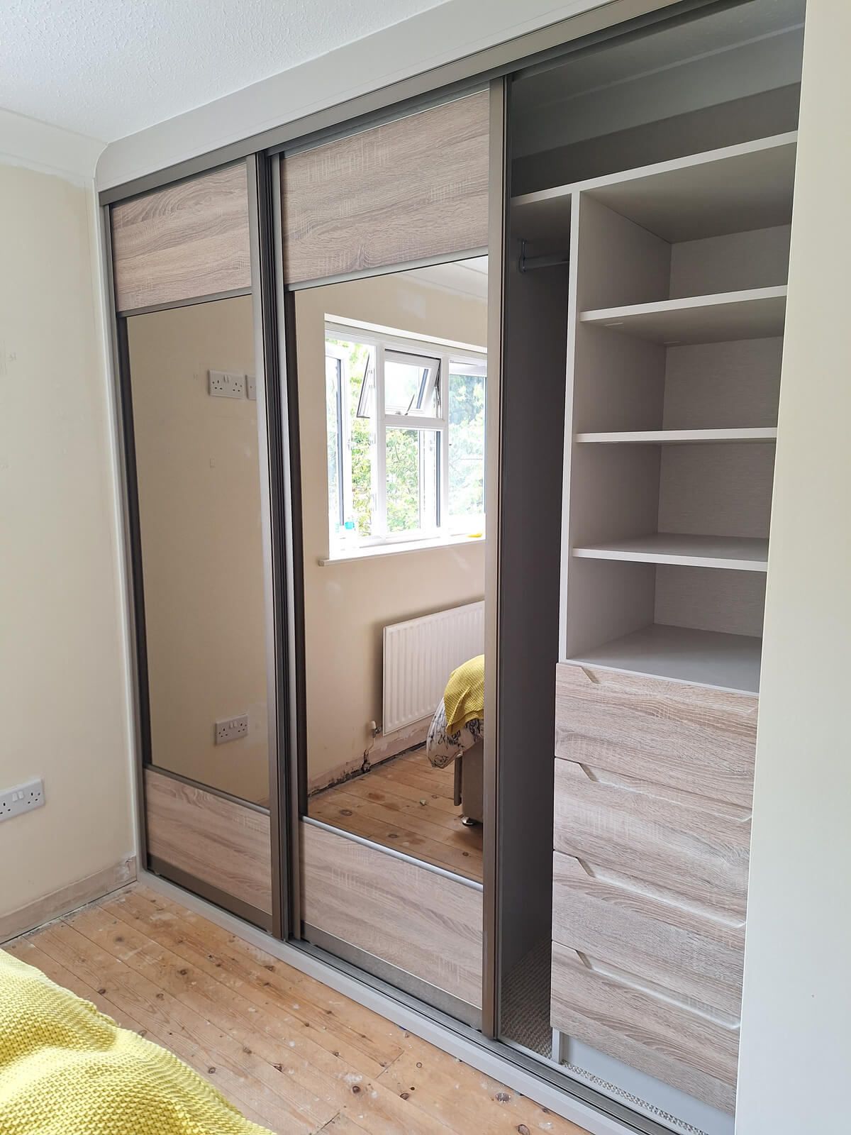 The same Stafford wardrobe with one door open, showing a custom shelf stack above a bank of Sonoma oak drawers