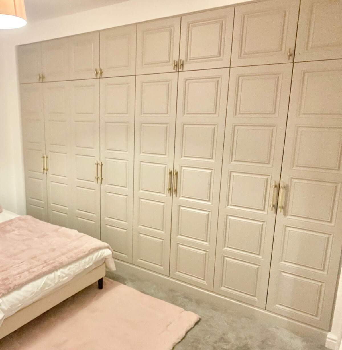Cashmere panelled fitted wardrobes with a bed and dressing mirror in a Sutton Coldfield bedroom