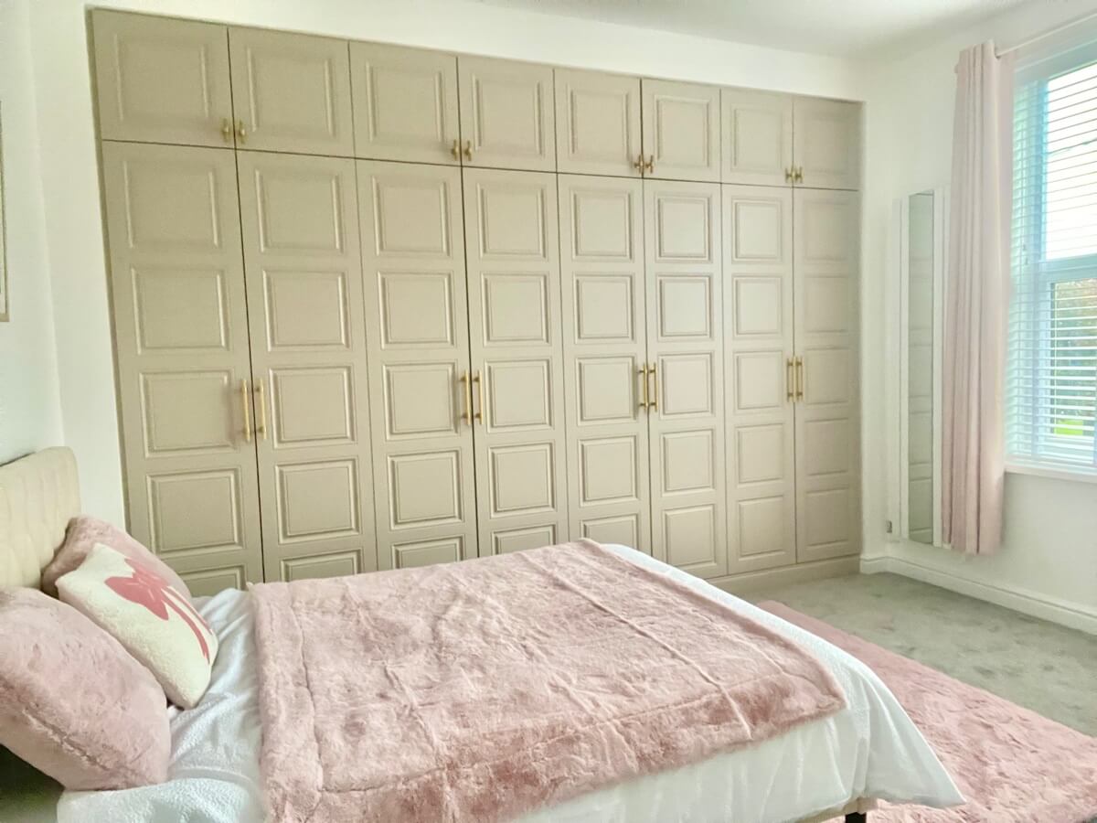 Floor-to-ceiling cashmere panelled fitted wardrobes with brass handles in a Sutton Coldfield bedroom