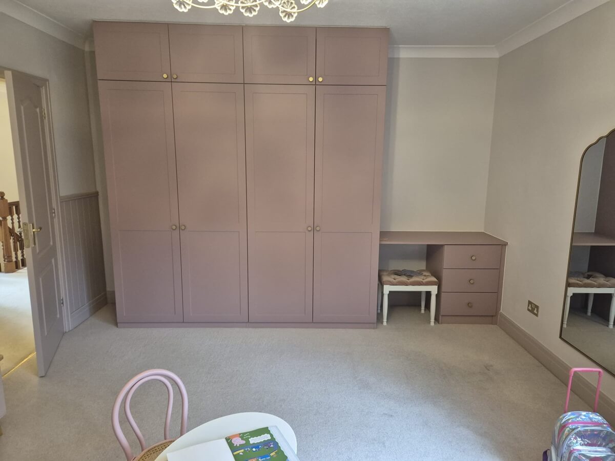 Dusky pink shaker fitted wardrobe with a desk in a child's bedroom in Sutton Coldfield