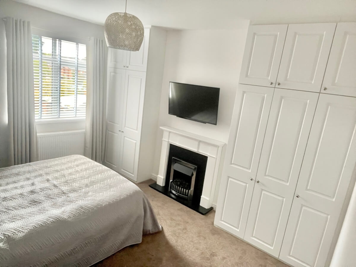 White panelled fitted wardrobes built into the alcoves either side of a chimney breast in a Sutton Coldfield bedroom