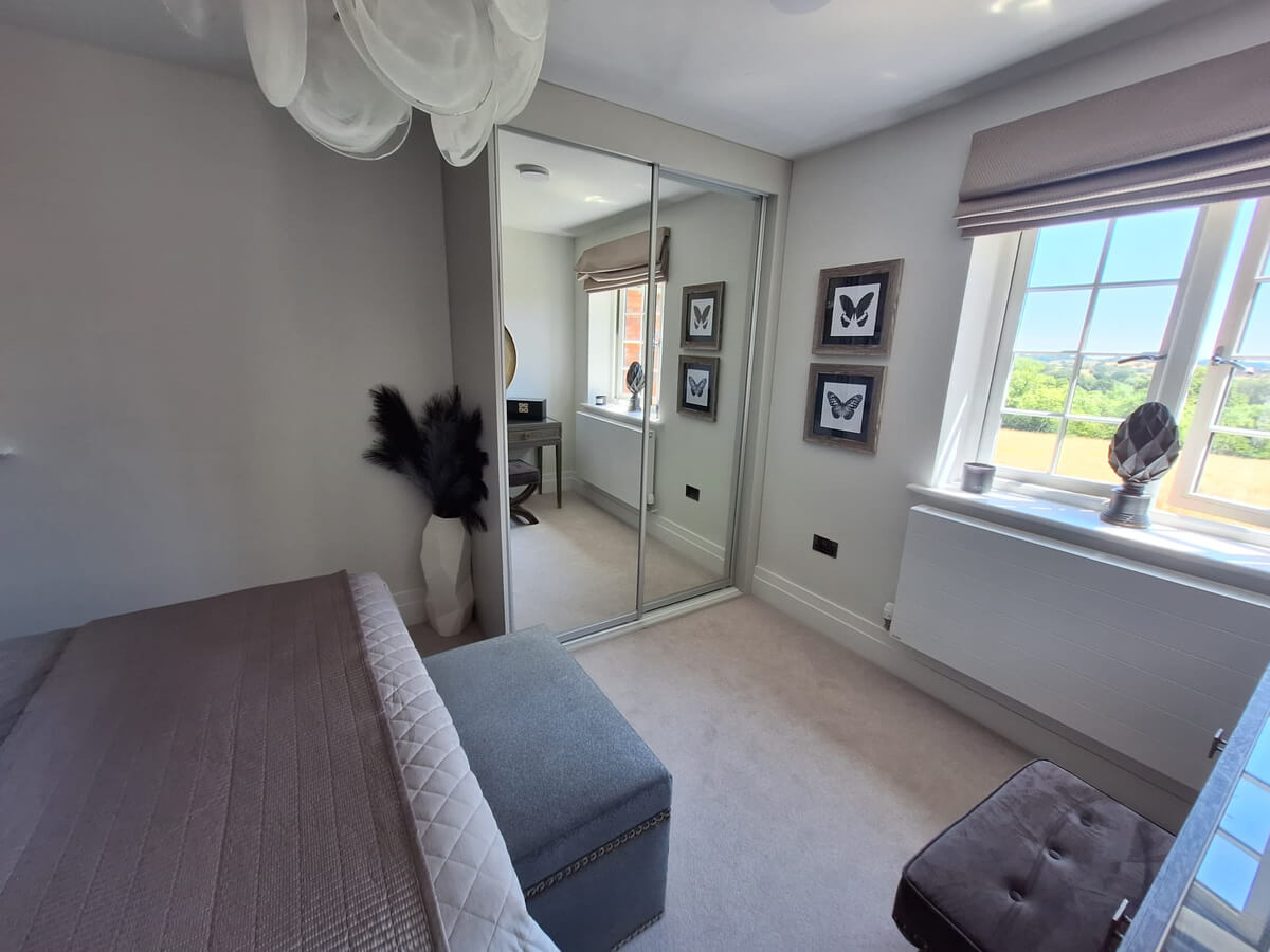 Two silver mirror sliding doors on a FORM frame fitted into a recess in the corner of a Tamworth bedroom
