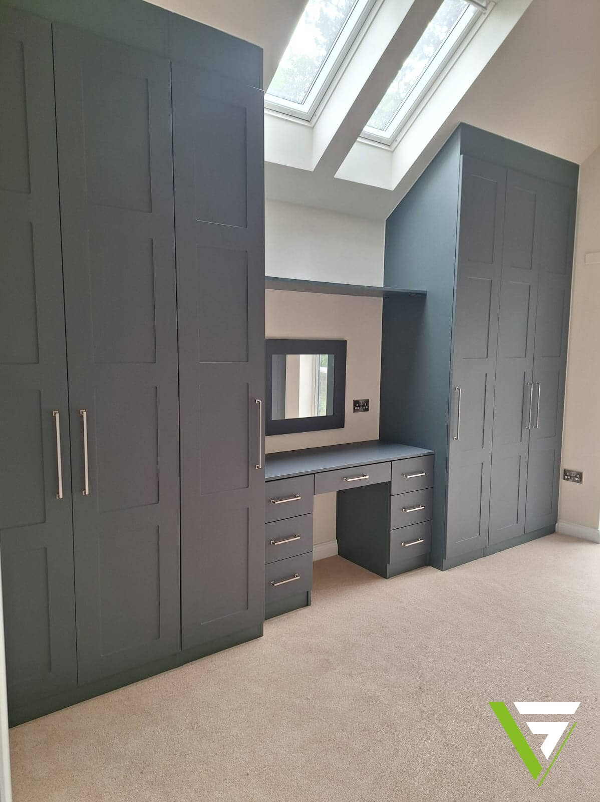 Heritage Green hinged wardrobes either side of a built-in dressing table under roof windows and a sloping ceiling in a Tamworth bedroom