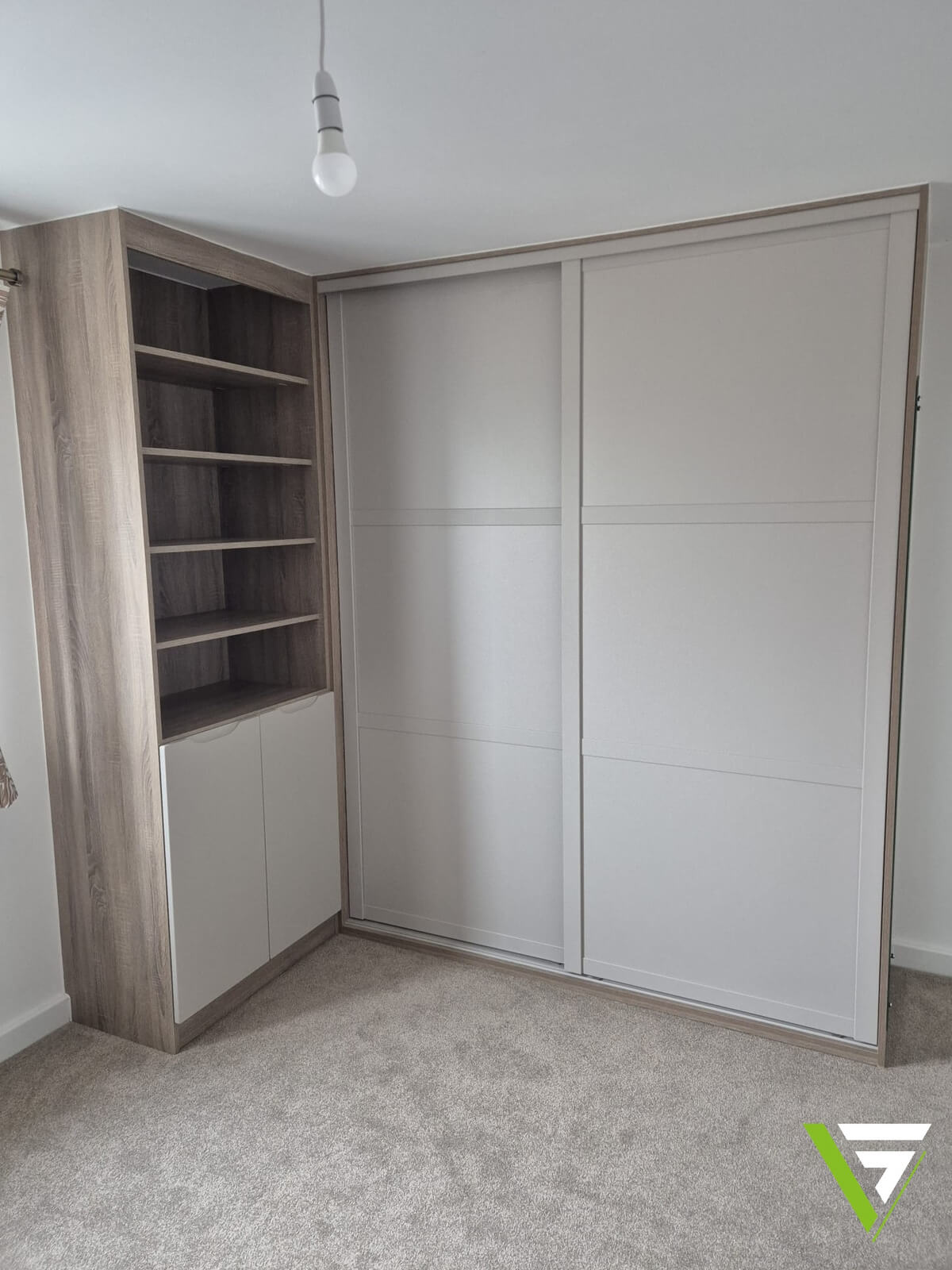 Two Cashmere SHAKER sliding wardrobe doors in oak-effect woodwork with a bookcase alongside, fitted under a sloping ceiling in Tamworth