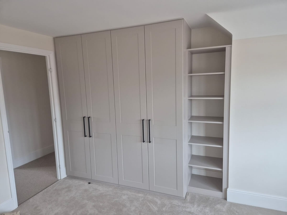 Cashmere shaker-style hinged fitted wardrobe with black bar handles and an open shelf tower fitted into the eaves