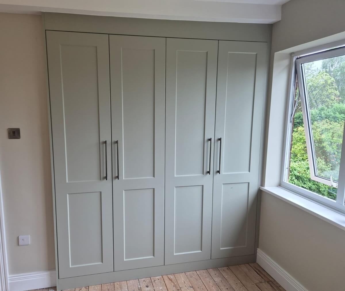 Supermatt sage green shaker-style hinged wardrobes with black bar handles, Coventry bedroom