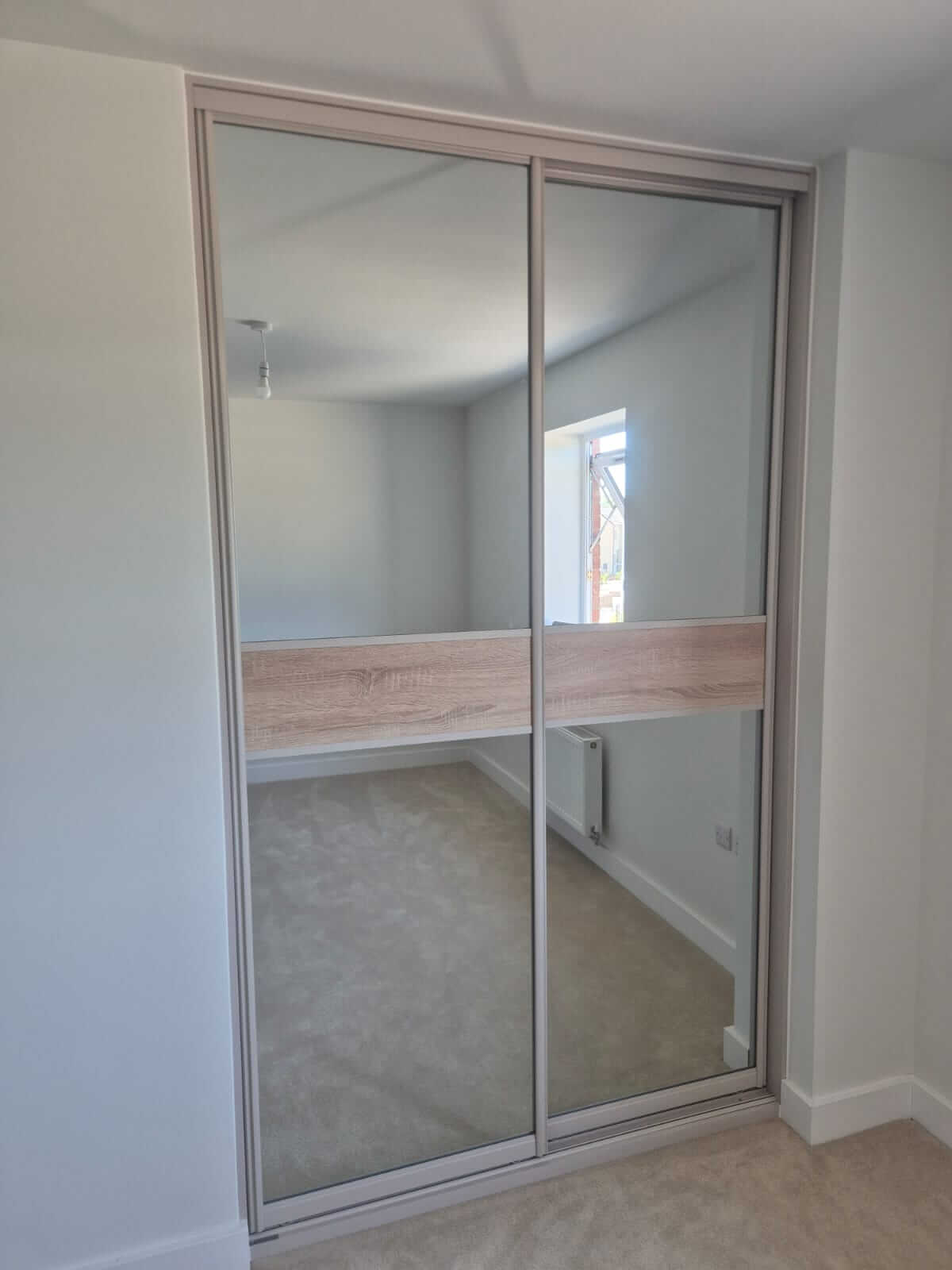 Two-door silver mirror sliding wardrobe with a Grey Nebraska Oak split on a cashmere frame — sliding wardrobe specialists in Sutton Coldfield
