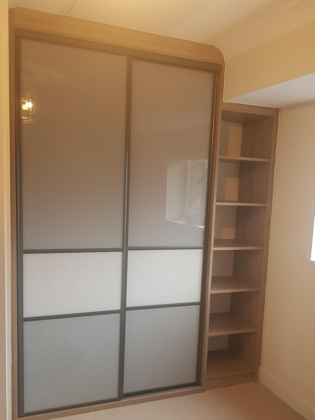 Two-door Storm Grey sliding wardrobe with an open oak-effect shelf tower beside it in Stafford