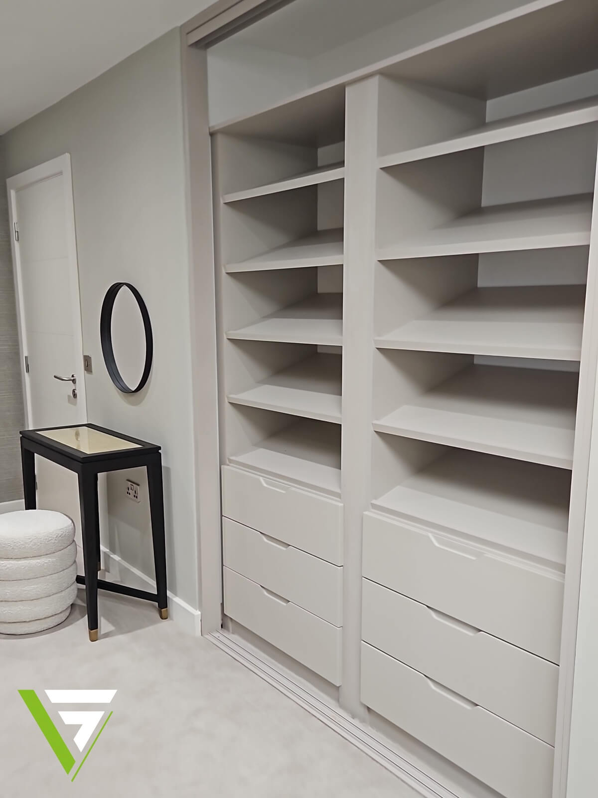 Fitted wardrobe interior with open shelving towers, drawer banks and a dressing area with a round mirror
