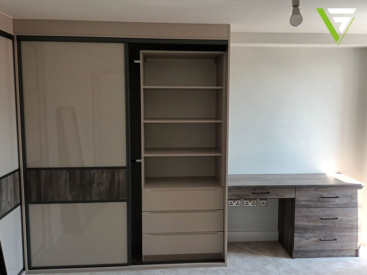 Open fitted wardrobe interior with an adjustable shelf tower, soft-close drawers and a built-in desk, in a graphite finish