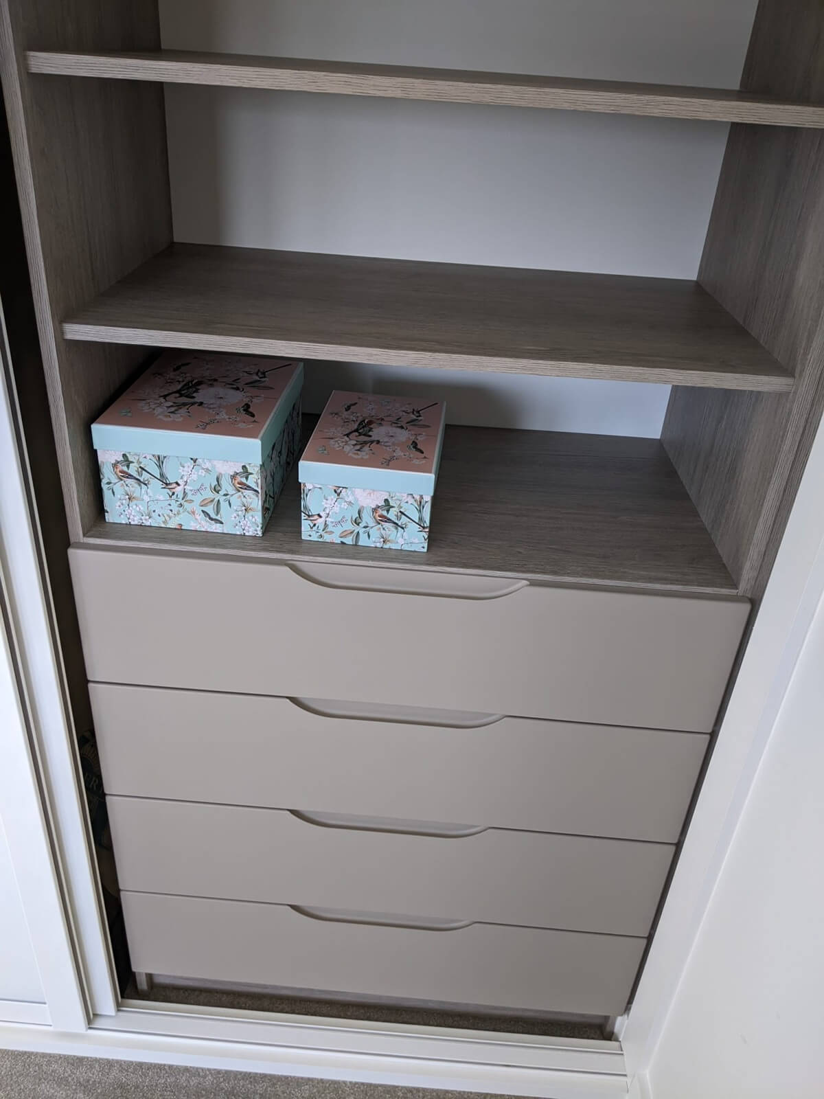 Wardrobe interior with cashmere shelves, a hanging rail and drawers, storing dresses, boxes and accessories
